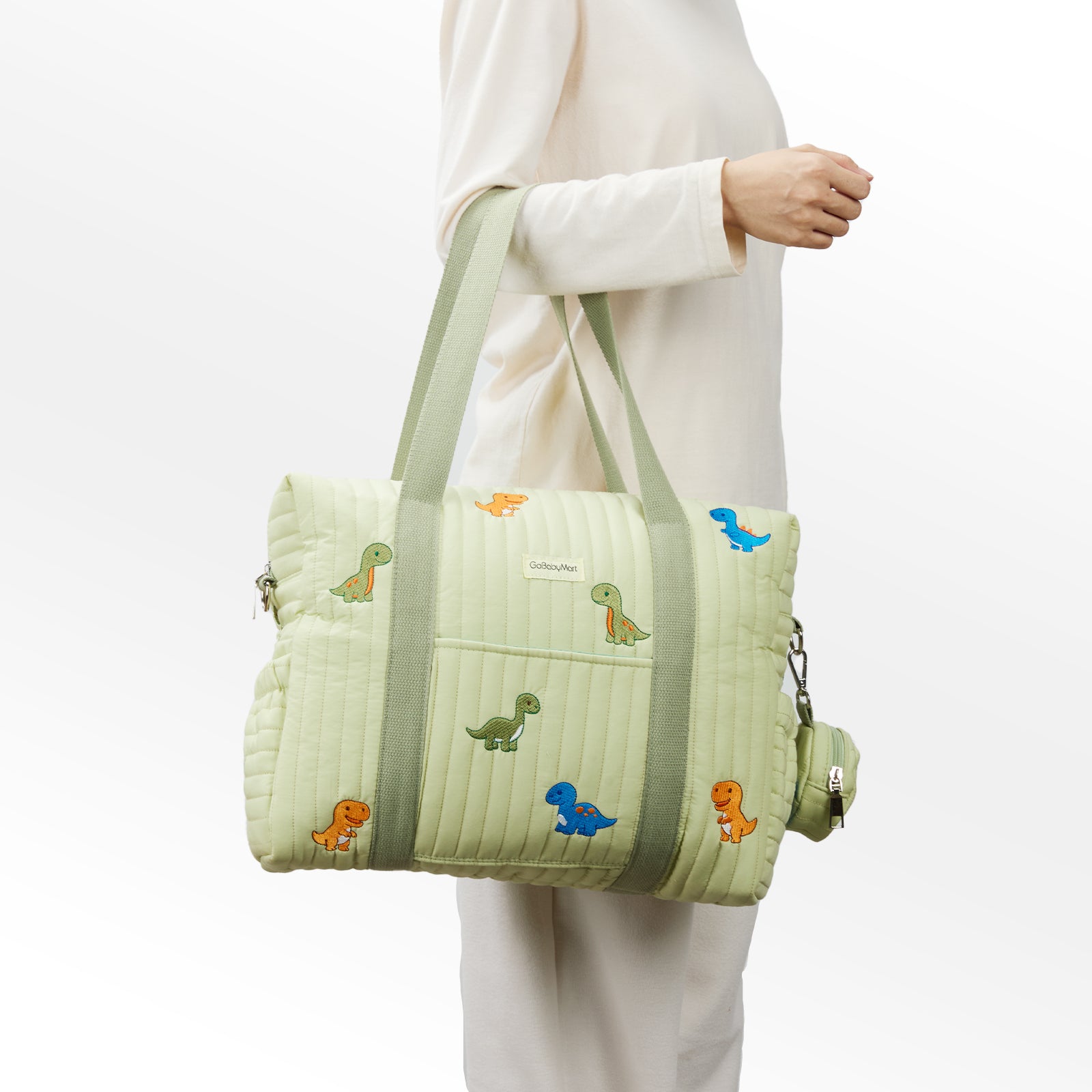 Light green quilted Diaper bag tote with dinosaur embroidery held by a person wearing a white outfit. #Color_Green Dinosaurs