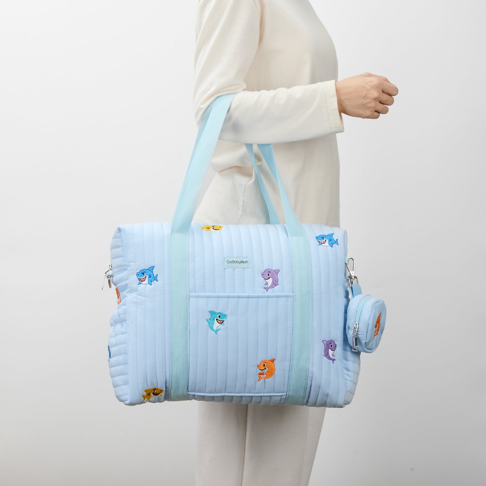 Light blue quilted Diaper bag with cartoon characters held by a person in a white coat. #Color_Blue Sharks