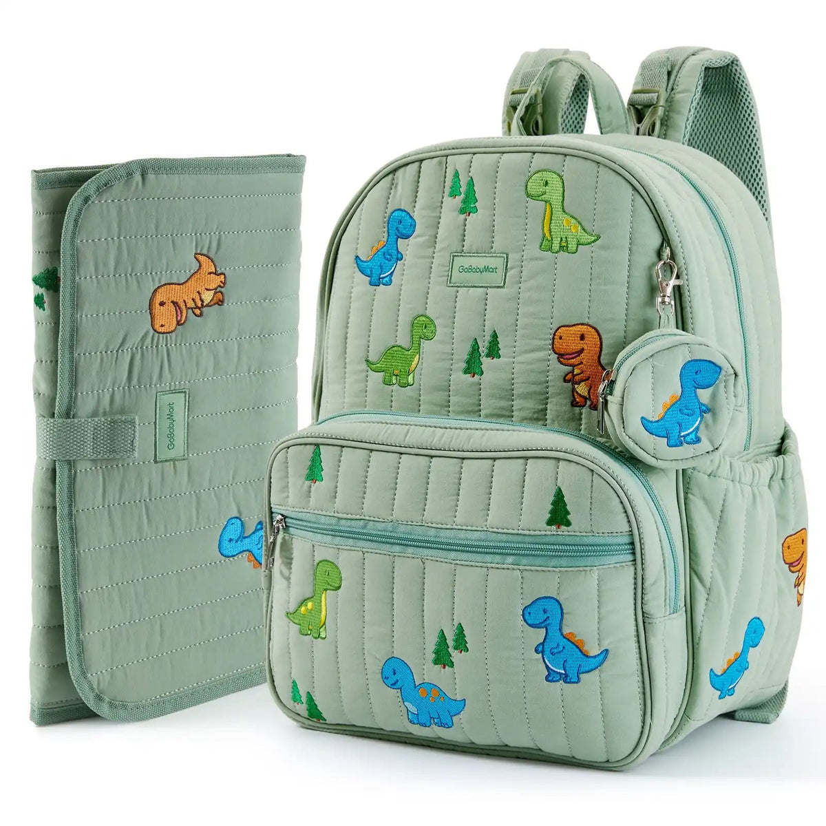 A light sage green quilted baby diaper bag backpack with colorful dinosaur and tree prints, shown alongside a matching zippered pouch and a folded changing pad on a white background. #Color_Green - Dinosaurs