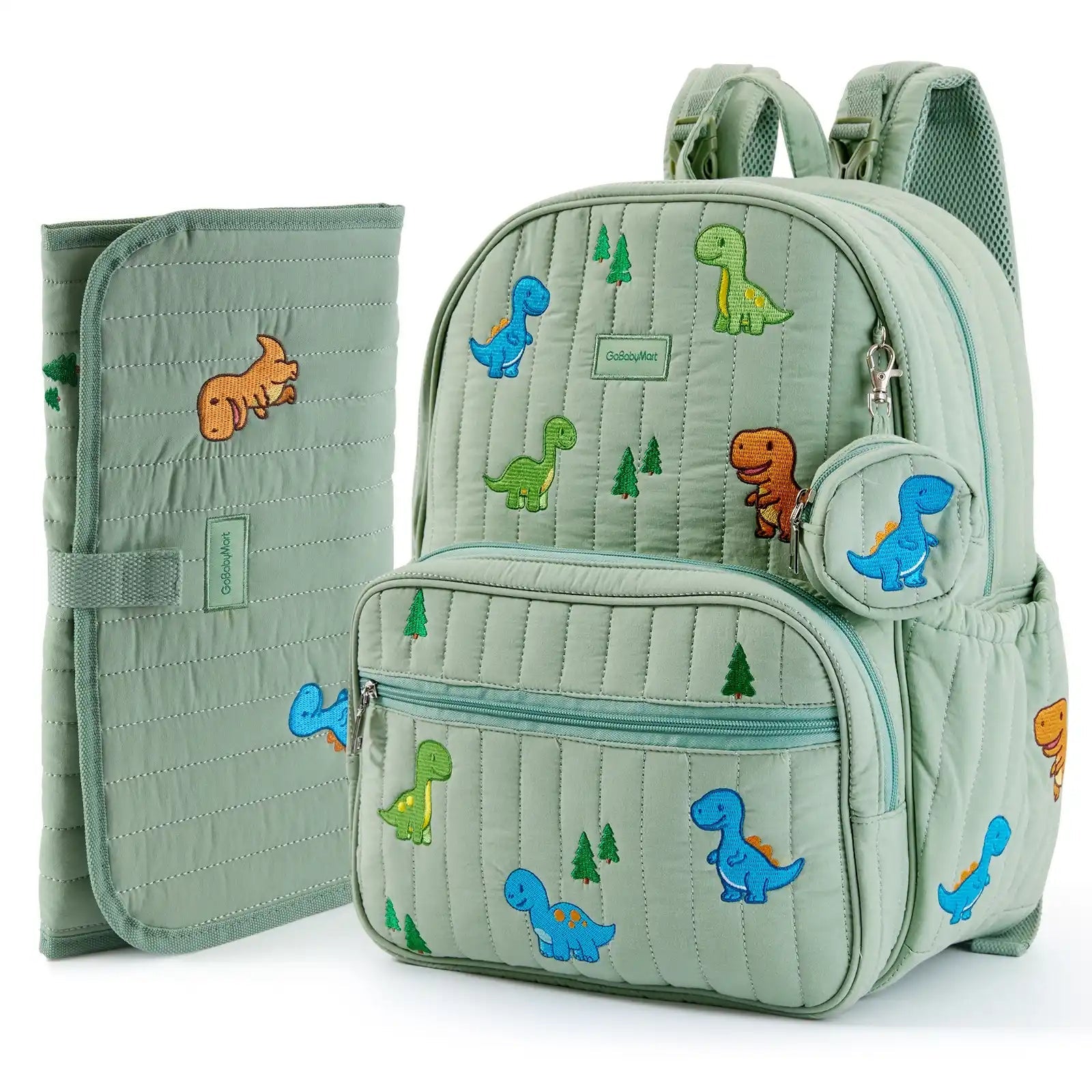 A light sage green quilted baby diaper bag backpack with colorful dinosaur and tree prints, shown alongside a matching zippered pouch and a folded changing pad on a white background. #Color_Green - Dinosaurs